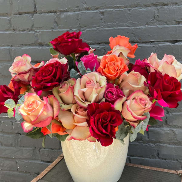 Bouquet of red, pink, and peach roses in a white vase