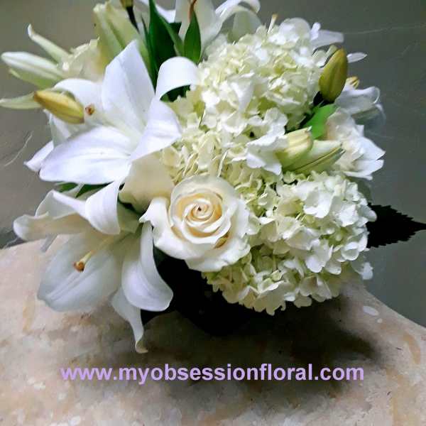 White lilies and hydrangeas arranged with a white rose