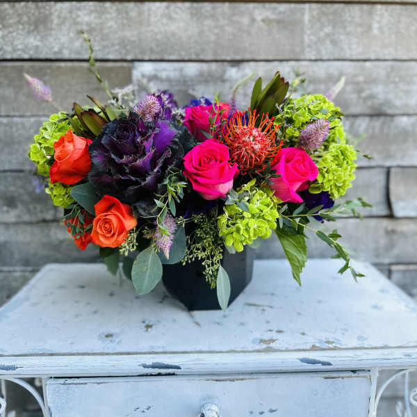 Colorful mixed bouquet in a black container with roses and bright green blooms