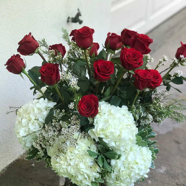 Red roses and white hydrangeas in a clear glass vase