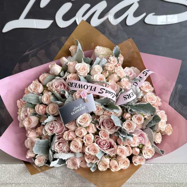 Large bouquet of pale pink roses wrapped in pink and brown paper