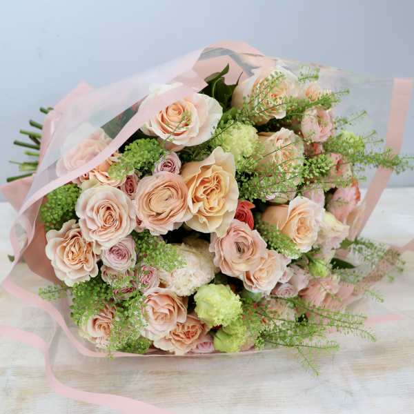 Bouquet of peach roses with lime-green accents wrapped in pink and clear cellophane