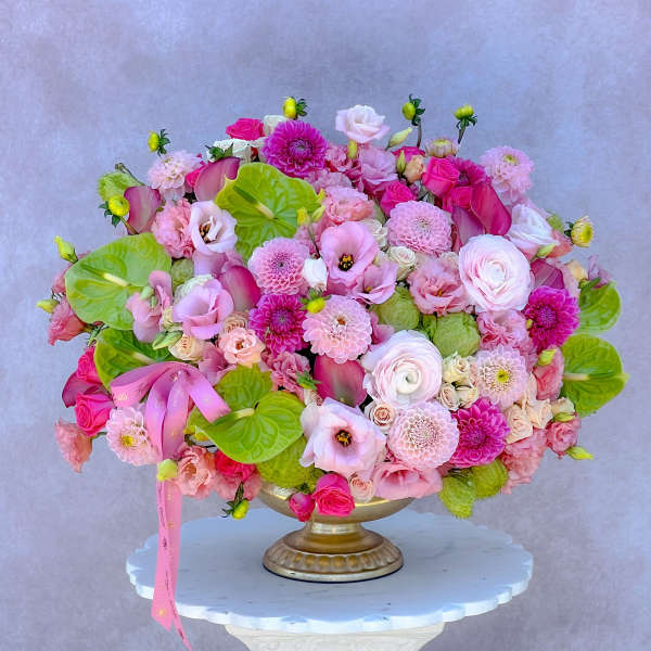Pink and white floral arrangement in a gold pedestal vase