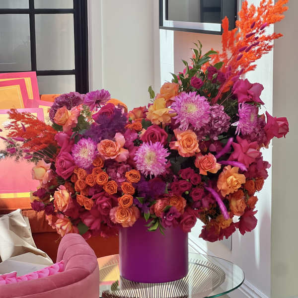 Large bouquet of pink, orange, and purple flowers in a magenta vase