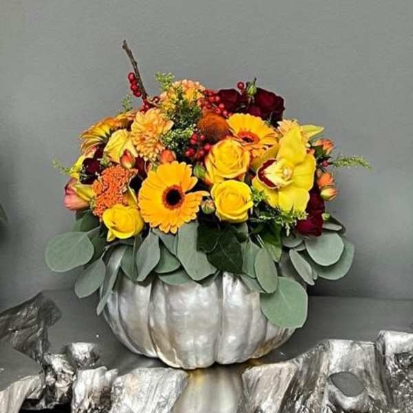 Yellow and burgundy floral arrangement in a silver pumpkin container
