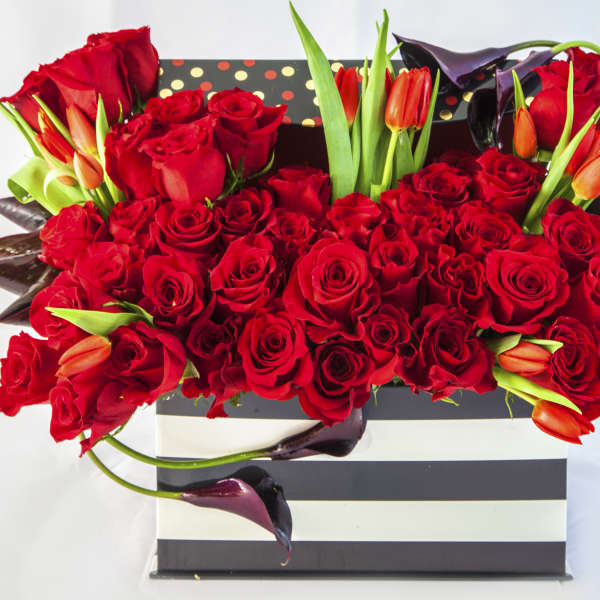 Red roses and orange tulips in a striped gift box