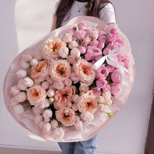 Large bouquet of pink and peach roses wrapped in pale pink paper
