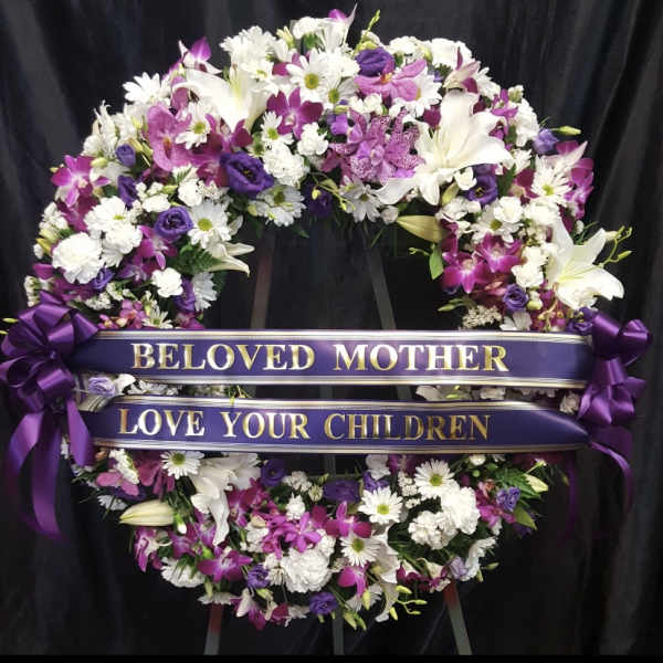 Purple and white floral funeral wreath with ribbon banners