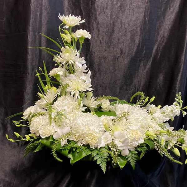 White floral arrangement with a tall central spray and low spread of blooms
