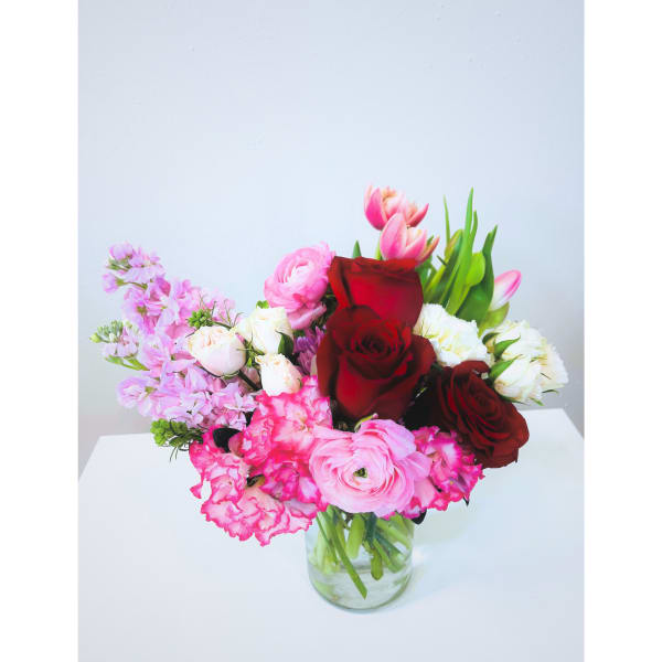 Mixed bouquet of red, pink, and white flowers in a clear glass vase
