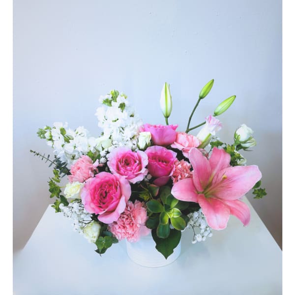 Pink and white floral arrangement in a white vase with lilies and roses
