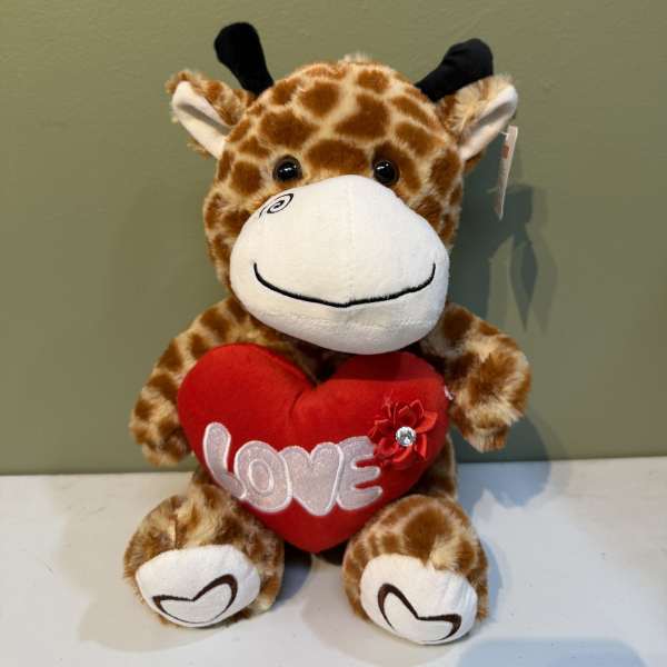 Plush giraffe holding a red heart with the word LOVE