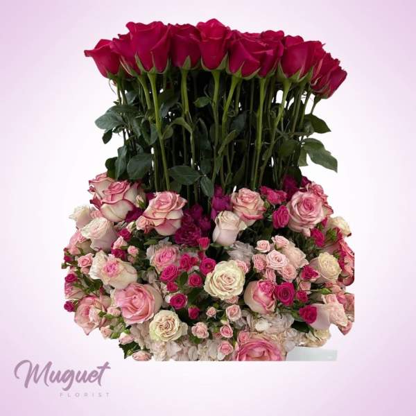 Tall arrangement of red and pink roses with a dense base of blush roses