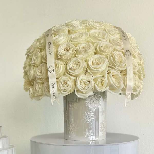 Cream rose bouquet in a silver vase with ribbon accents