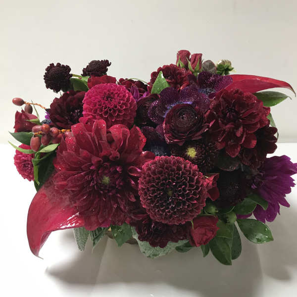 Deep burgundy and magenta bouquet with mixed blooms in a low arrangement