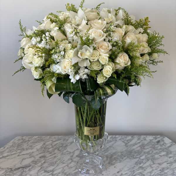 Large white rose arrangement in a clear glass vase