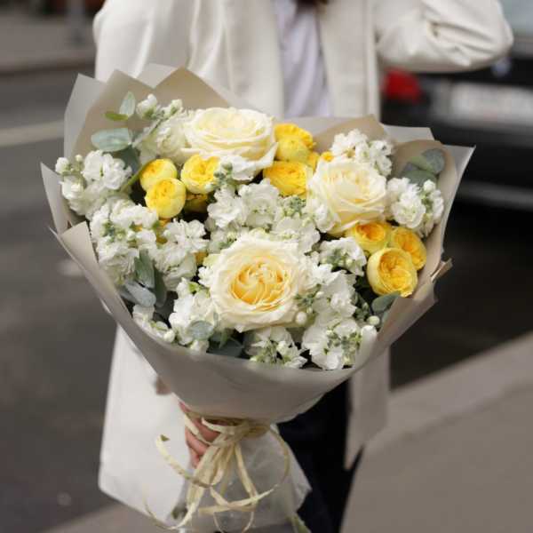Bouquet of white and yellow roses wrapped in beige paper