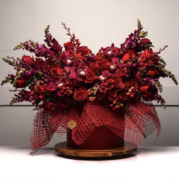 Large red floral arrangement in a round box with mesh wrap