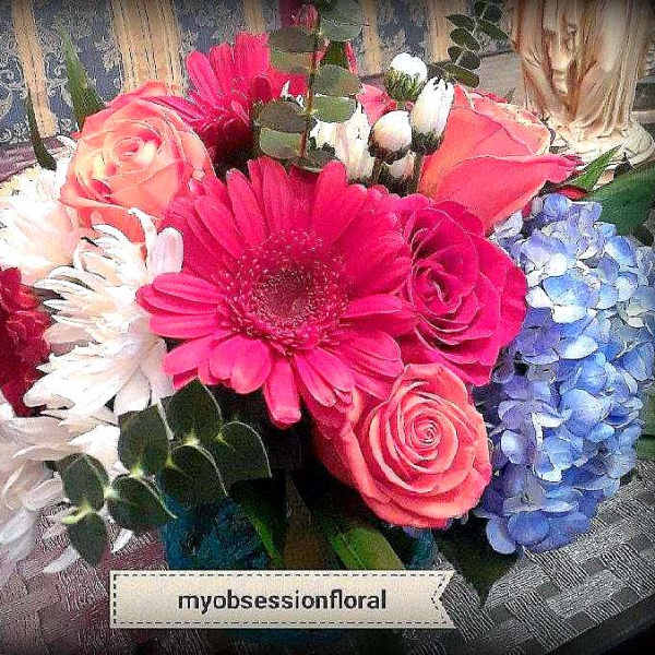 Mixed bouquet with pink gerbera daisies, roses, and blue hydrangeas