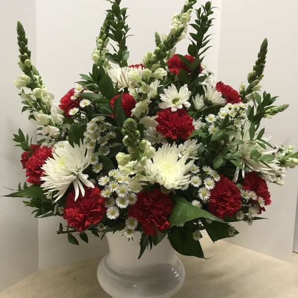 Red and white floral arrangement in a white vase