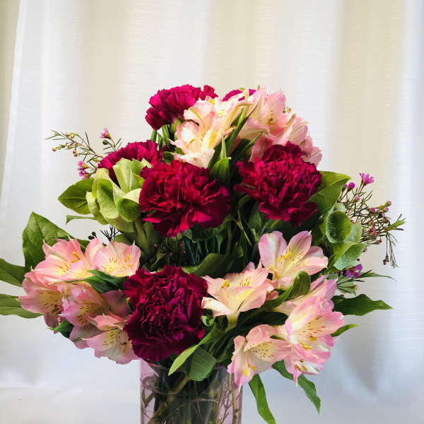 Pink and red bouquet of carnations and alstroemeria in a glass vase