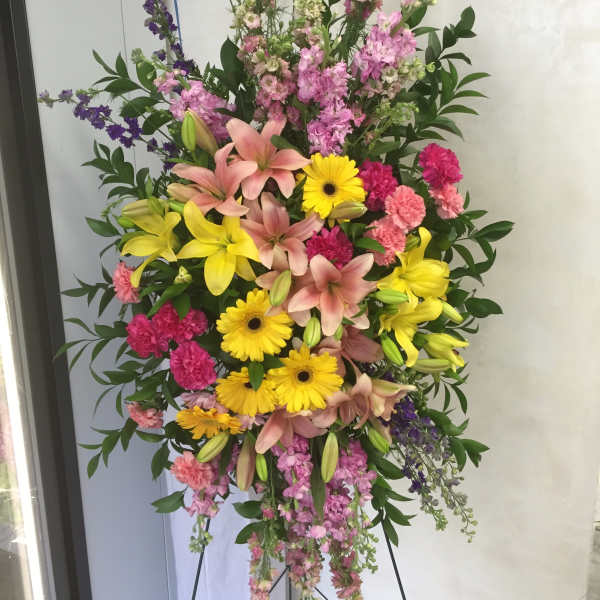 Tall standing floral spray with pink lilies, yellow gerberas, and mixed blooms