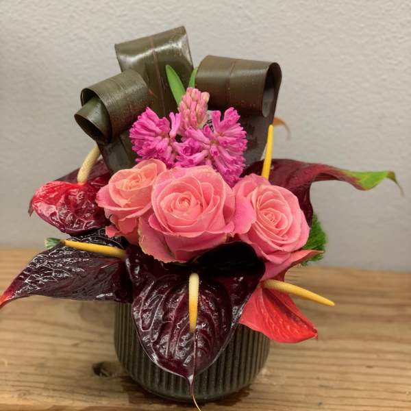 Pink roses and magenta flowers arranged in a small vase