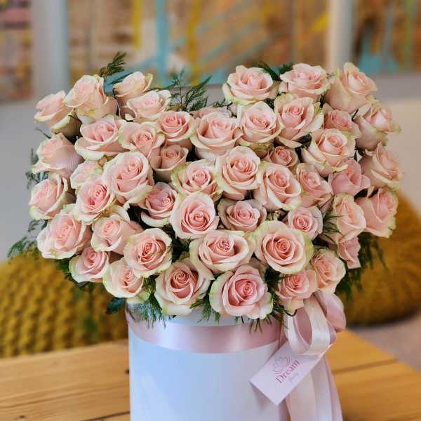 Pink roses arranged in a white hat box with a pink ribbon