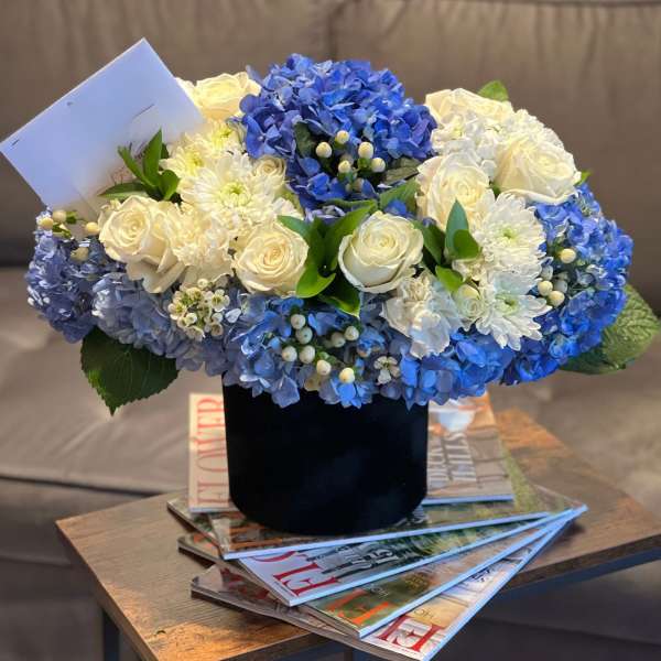 Blue and white floral arrangement in a black vase