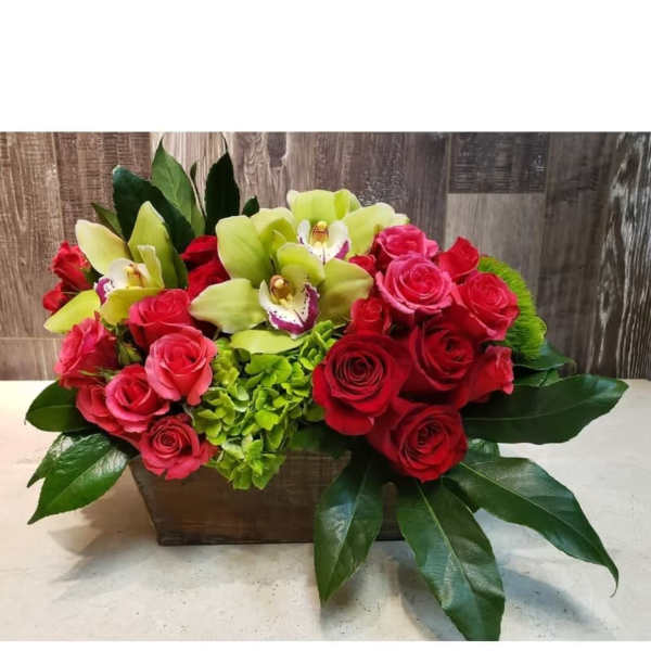Arrangement of red and pink roses with green orchids in a wooden box
