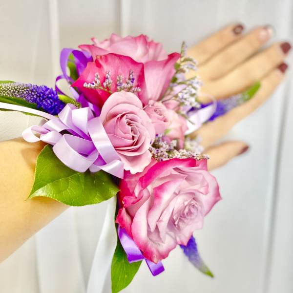 Pink rose wrist corsage with purple ribbon and small purple filler flowers