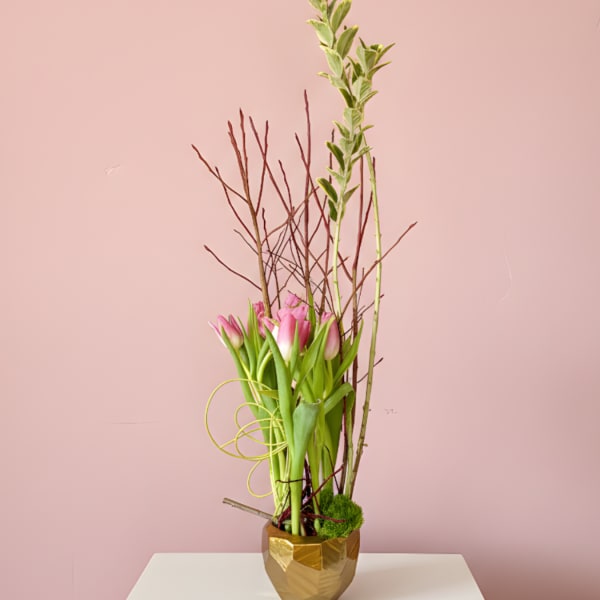 Tall arrangement of pink tulips in a gold vase