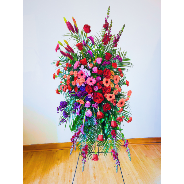 Tall standing arrangement of red, pink, and purple flowers