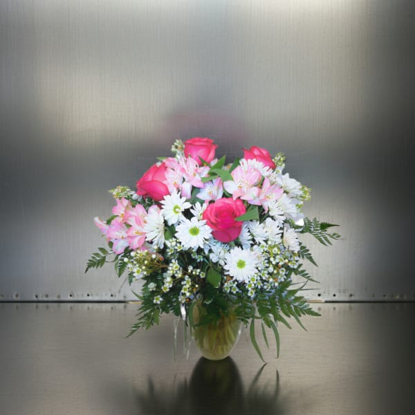 Bouquet of pink roses and white daisies in a clear glass vase