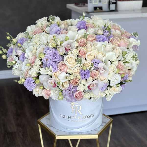 Large pastel bouquet of roses, orchids, and calla lilies in a white hat box