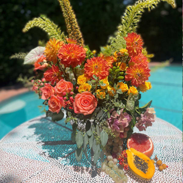 Bright mixed bouquet with orange dahlias and coral roses in a vase