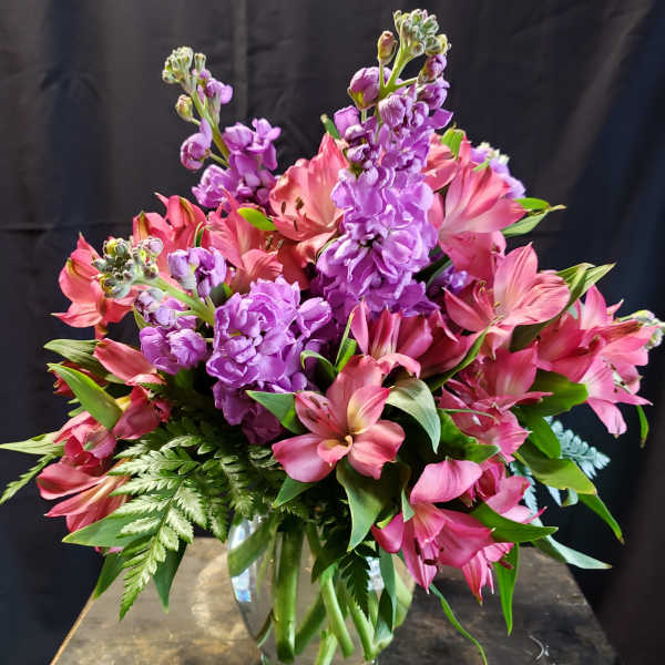 Pink and purple flowers arranged in a clear glass vase