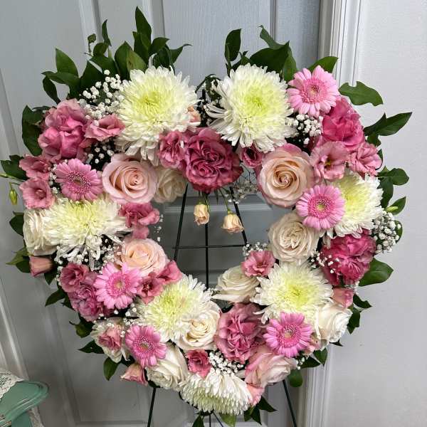 Heart-shaped floral wreath with pink and white flowers on a stand