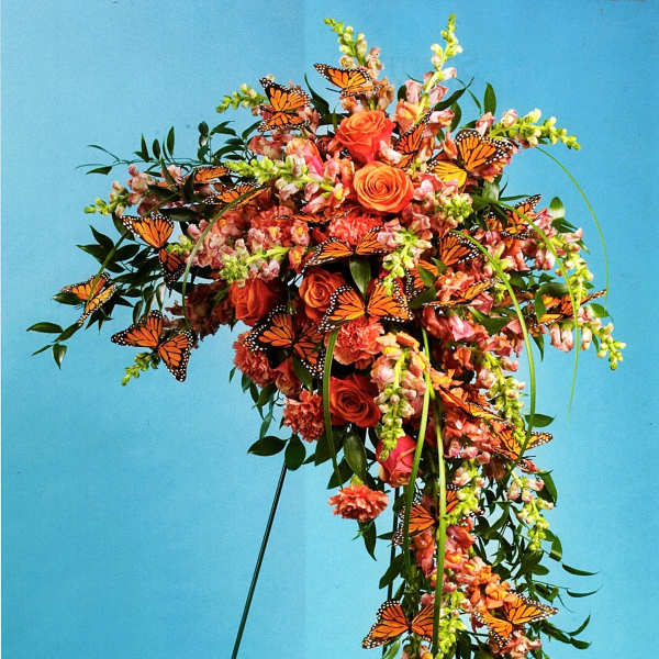 Orange floral standing spray with butterflies on a metal easel