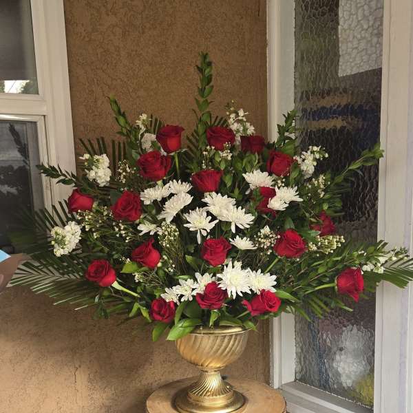 Red roses and white daisies in a gold urn on a pedestal