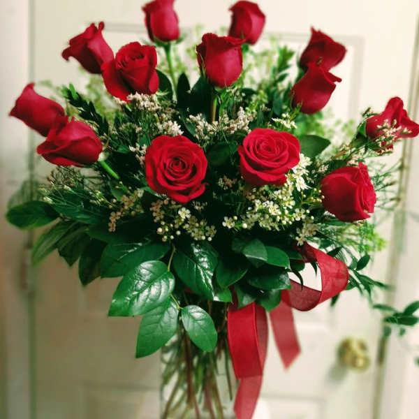 Bouquet of red roses in a clear glass vase with a red ribbon