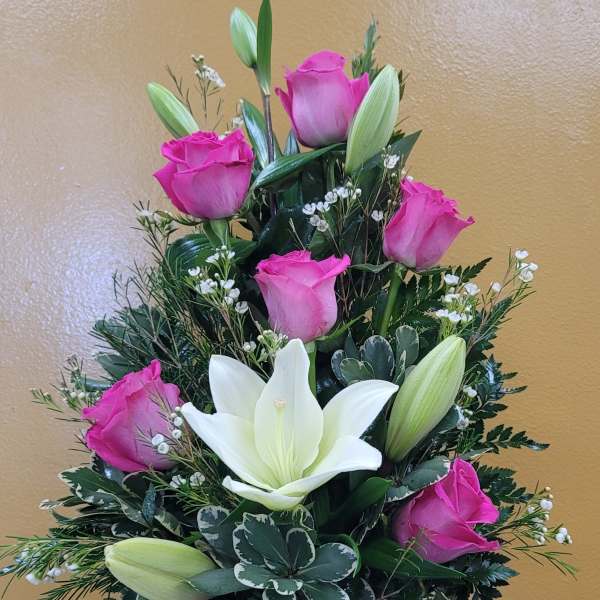 Pink roses and white lilies arranged in a red glass vase