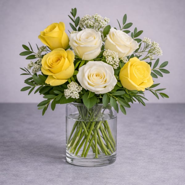 Yellow and white roses arranged in a clear glass vase