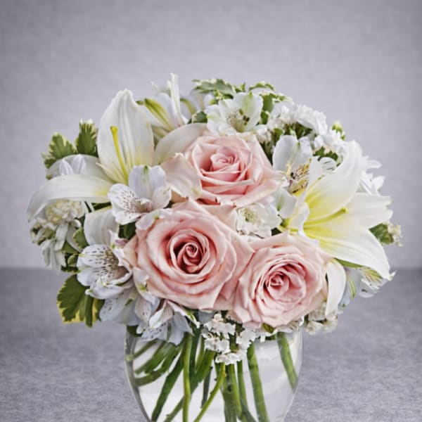 Pink roses and white lilies arranged in a clear glass vase