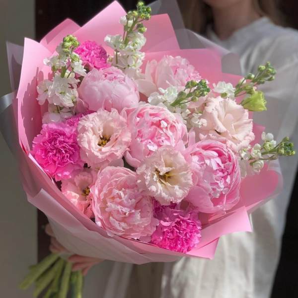 Pink bouquet of peonies, carnations, and white blooms wrapped in pink paper