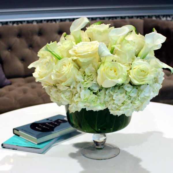 White roses and calla lilies arranged in a glass vase