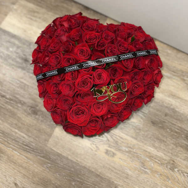 Heart-shaped bouquet of red roses with a black ribbon and gold "I love you" topper