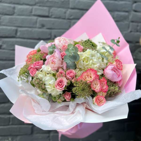 Pink and white bouquet of roses and hydrangeas wrapped in pastel paper