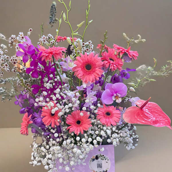 Bouquet of pink gerbera daisies and purple orchids with baby's breath