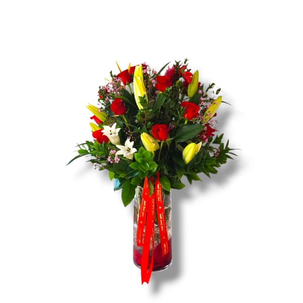 Bouquet of red roses and yellow lilies in a glass vase with a red ribbon